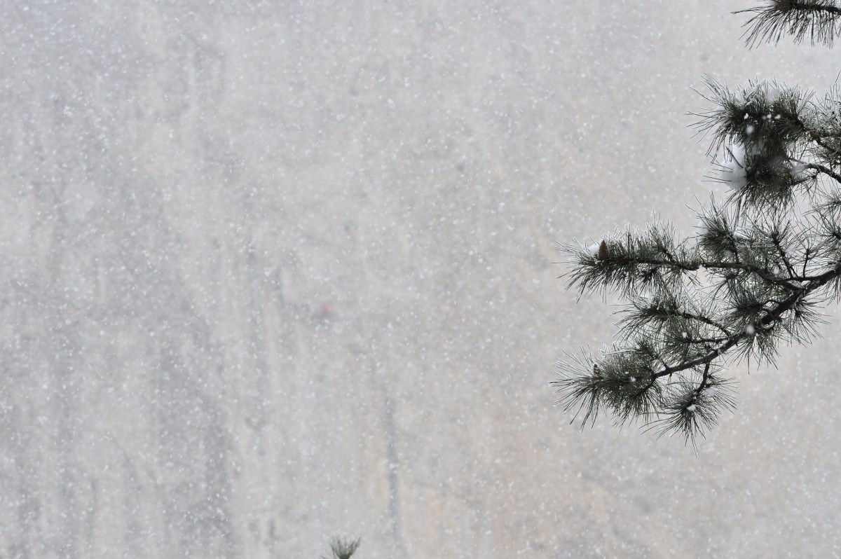 Через толщу падающего снега едва можно увидеть человека на стене